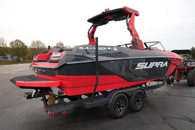 Slide: The Image of 2025 Supra SA 450 boat, red and black, on a trailer in a parking lot. - 4