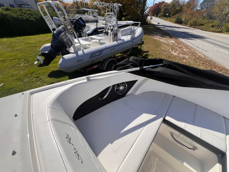 Slide: The Image of 2023 Sea Ray SPX 190 boat interior with white seating, parked near inflatable boats. - 12