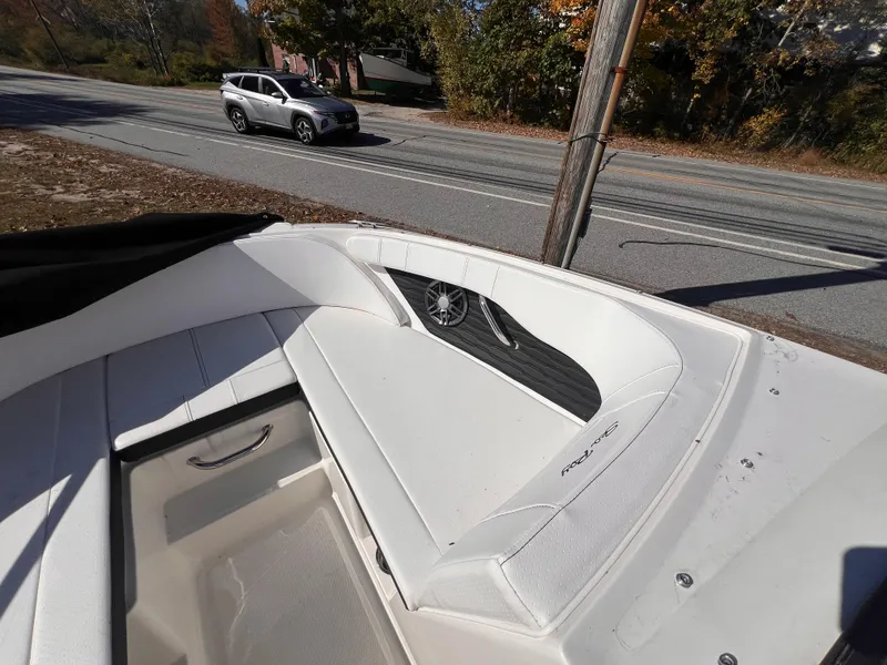 Slide: The Image of 2023 Sea Ray SPX 190 boat interior with white seating, parked near a road. - 14