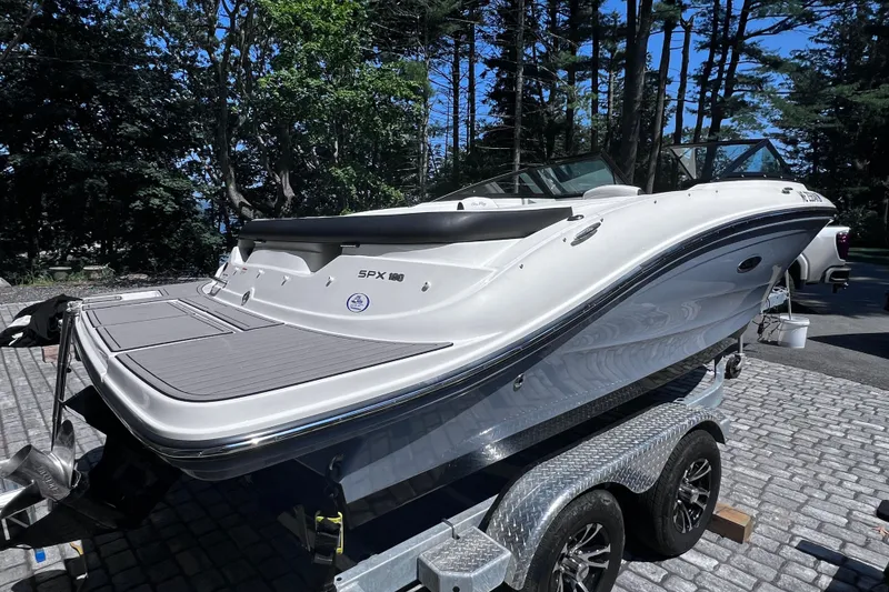 Slide: The Image of 2023 Sea Ray SPX 190 boat on trailer, surrounded by trees and parked on a cobblestone driveway. - 28