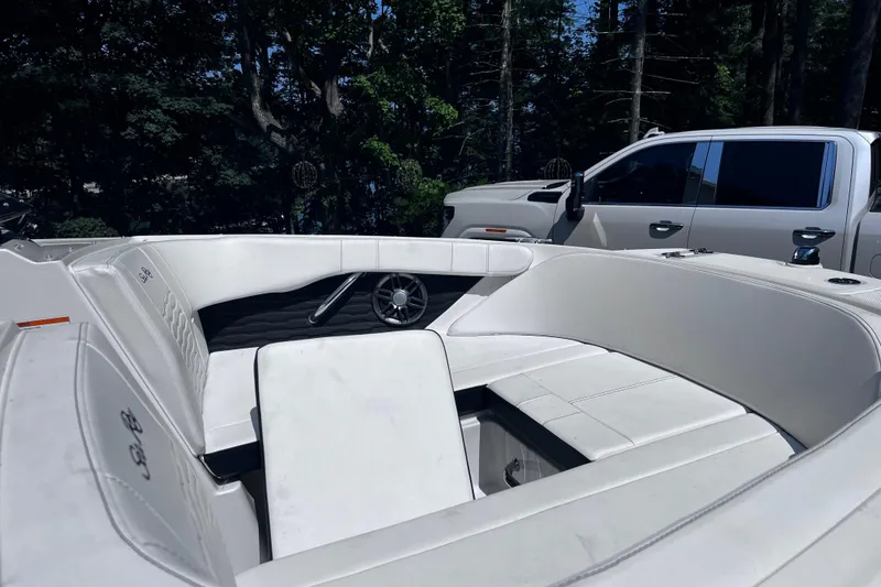 Slide: The Image of 2023 Sea Ray SPX 190 boat interior with white seating, parked near a truck. - 30