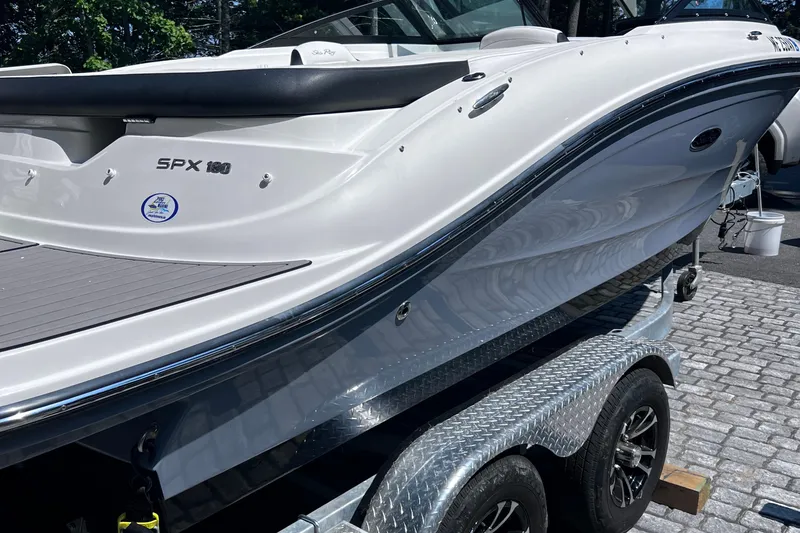 Slide: The Image of 2023 Sea Ray SPX 190 boat on trailer, sleek white design, parked on cobblestone surface. - 32