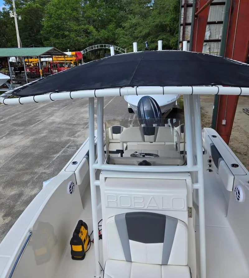 Slide: The Image of 2025 Robalo R180 Center Console boat with black T-top, docked outdoors. - 25