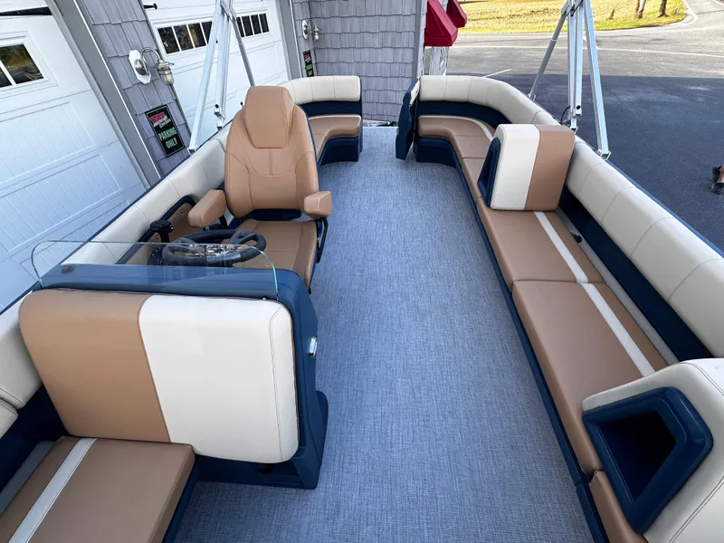 Slide: The Image of 2025 Avalon 2385 Aura Quad Lounge boat interior with tan and navy seating. - 13