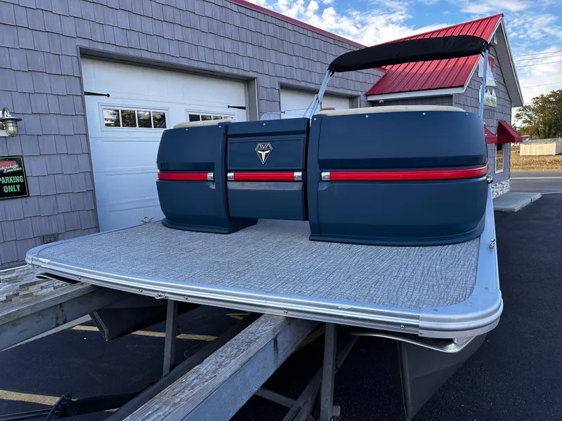 Slide: The Image of 2025 Avalon 2385 Aura Quad Lounge pontoon boat on trailer, parked near a building. - 3