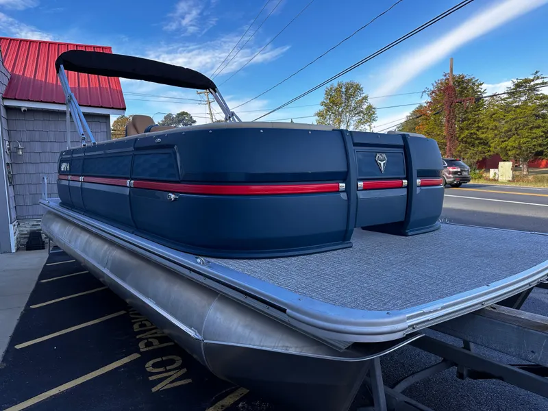 Slide: The Image of 2025 Avalon 2385 Aura Quad Lounge pontoon boat with sleek design, parked outdoors. - 6