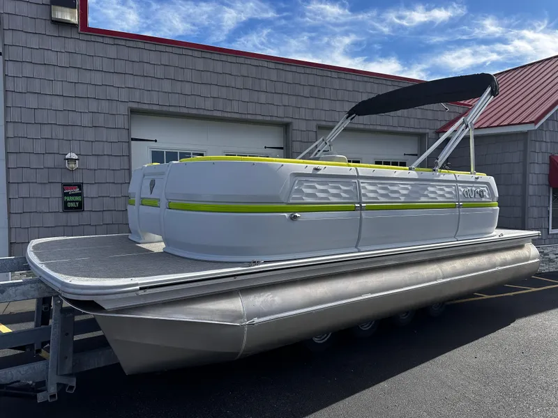 Slide: The Image of 2025 Avalon 2185 Aura Quad Lounge pontoon boat with canopy, parked outside a building. - 1