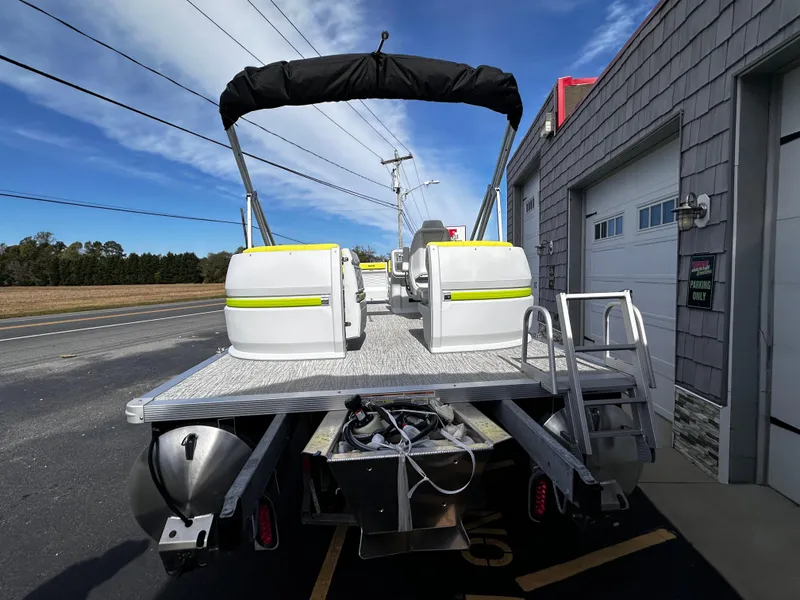 Slide: The Image of 2025 Avalon 2185 Aura Quad Lounge pontoon boat, parked near a building, rear view. - 6