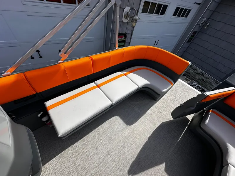 Slide: The Image of 2025 Avalon 2385 Aura Quad Lounge boat interior with orange and gray seating. - 16