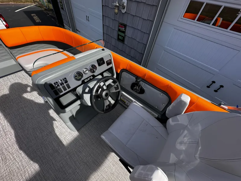 Slide: The Image of 2025 Avalon 2385 Aura Quad Lounge boat interior with orange seating and modern dashboard. - 17