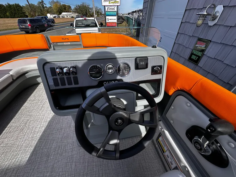 Slide: The Image of 2025 Avalon 2385 Aura Quad Lounge boat dashboard with orange seating and modern controls. - 18