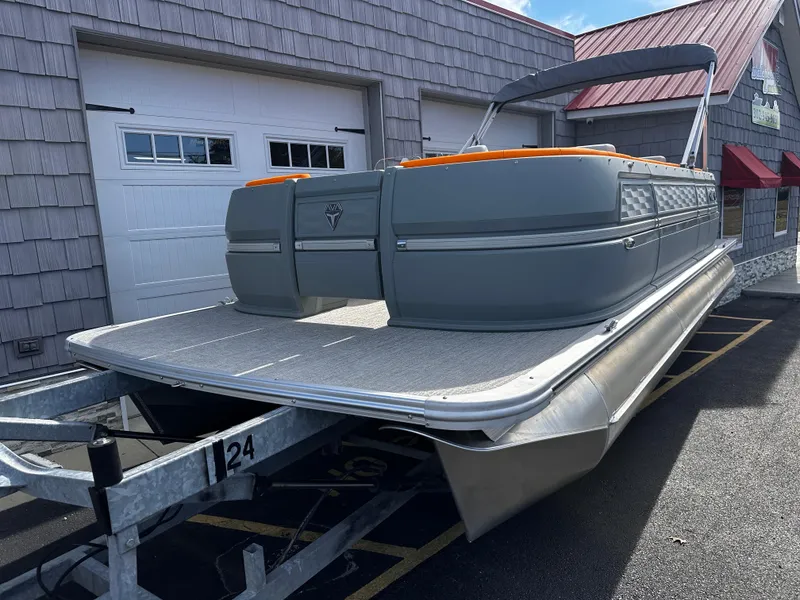 Slide: The Image of 2025 Avalon 2385 Aura Quad Lounge pontoon boat on trailer, parked outside. - 2