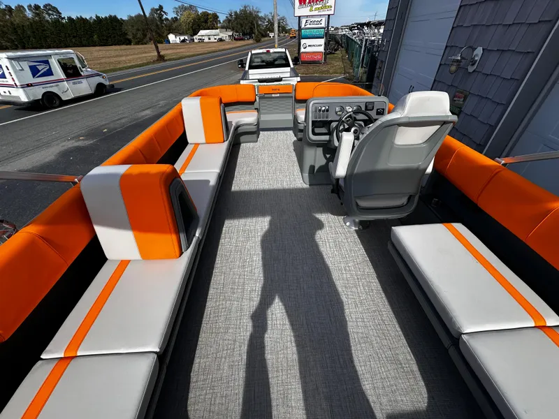 Slide: The Image of 2025 Avalon 2385 Aura Quad Lounge boat interior with orange and gray seating. - 22
