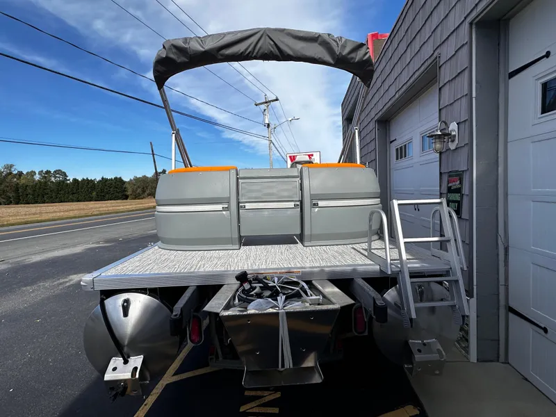 Slide: The Image of 2025 Avalon 2385 Aura Quad Lounge pontoon boat, rear view with canopy and ladder. - 5