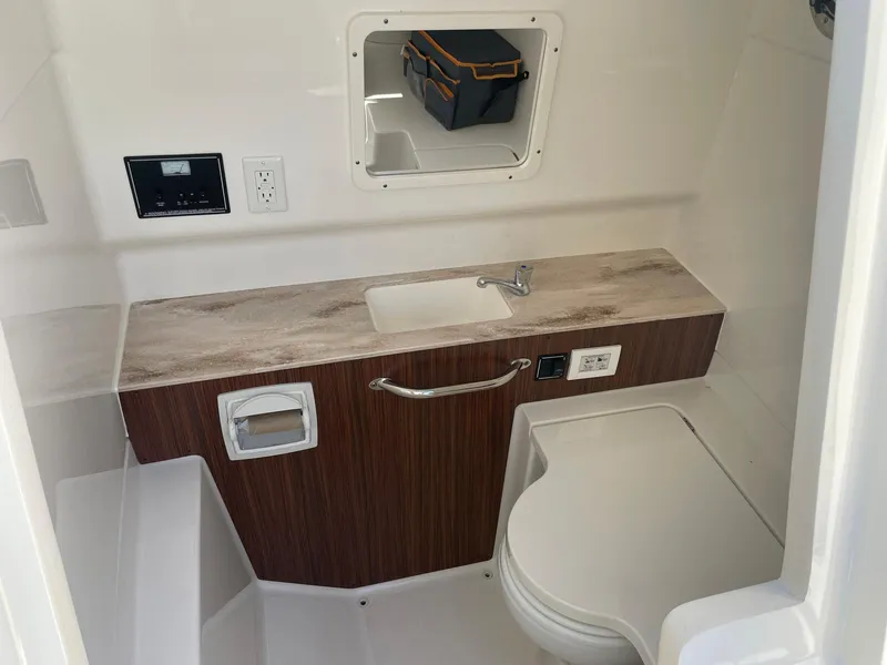 Slide: The Image of 2020 Pursuit S 288 boat bathroom with sink, toilet, and storage compartment. - 11