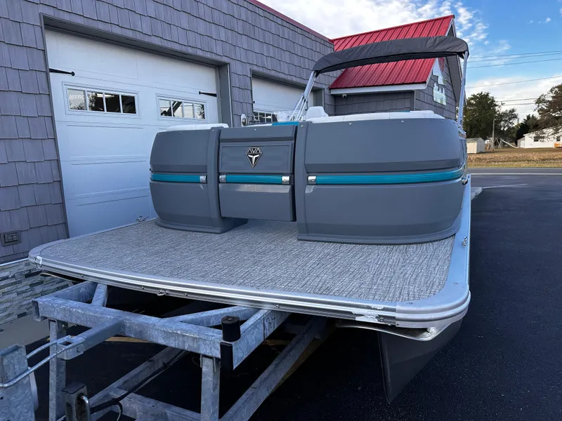 Slide: The Image of 2025 Avalon 2385 Aura Quad Lounge pontoon boat on trailer, parked near garage. - 3