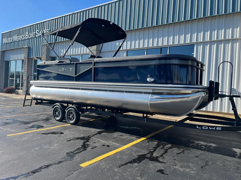 Slide: The Image of 2025 Lowe LS 230 WT pontoon boat on trailer outside dealership. - 2