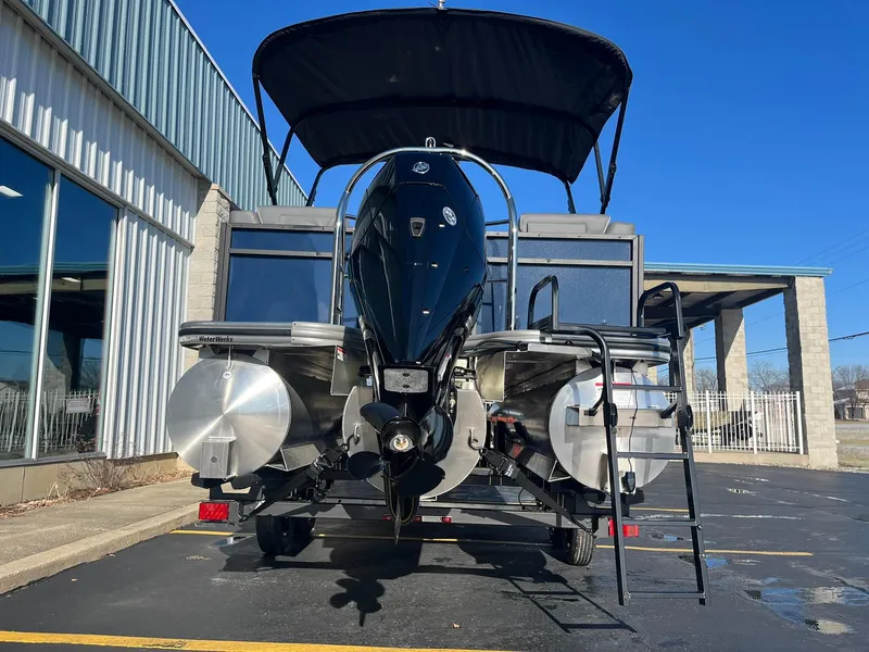Slide: The Image of 2025 Lowe LS 230 WT boat with outboard motor and canopy, parked outside a building. - 28