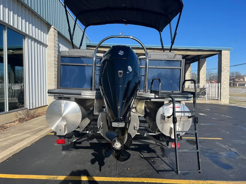 Slide: The Image of 2025 Lowe LS 230 WT pontoon boat with outboard motor and ladder, parked outdoors. - 4