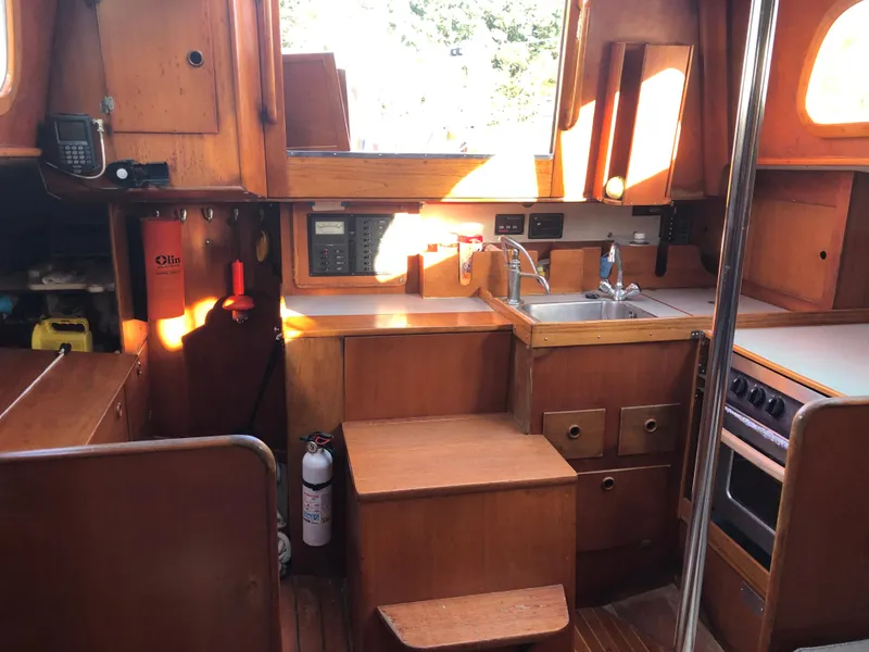 Slide: The Image of Interior of 1968 LeComte Northeast 38 sailboat, featuring wooden cabinetry and compact kitchen area. - 39
