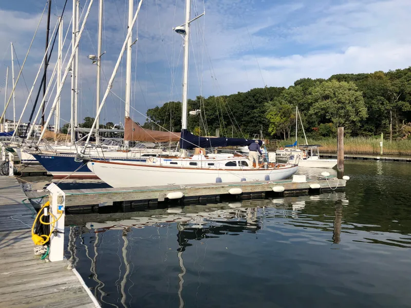 Slide: The Image of 1968 LeComte Northeast 38 sailboat docked at a marina with lush greenery in the background. - 5