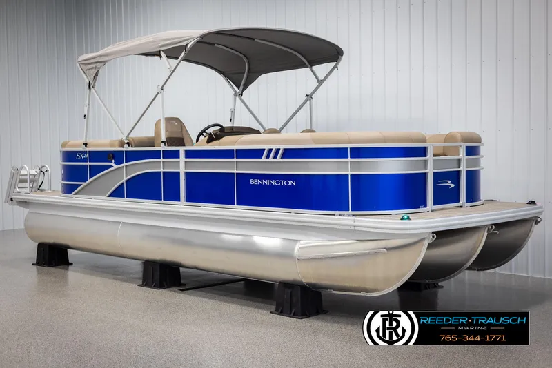 Slide: The Image of 2025 Bennington 23 SXPDSE pontoon boat with blue exterior and canopy in showroom. - 3