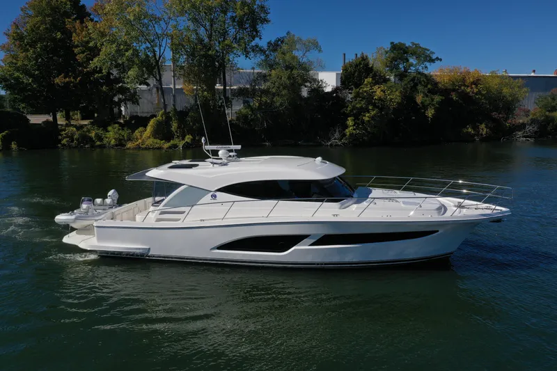 Slide: The Image of 2025 Riviera 465 SUV yacht cruising on a serene river under a clear blue sky. - 4