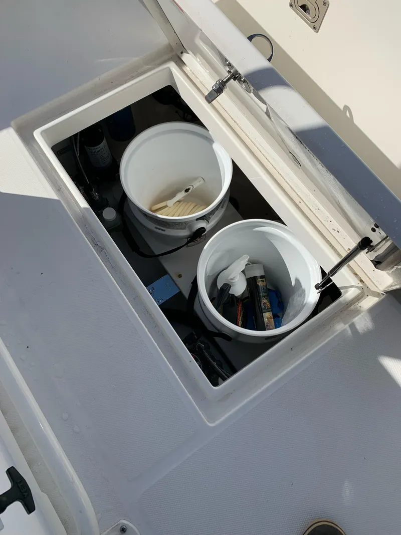 Slide: The Image of 2019 Regulator 23 FS boat storage compartment with cleaning supplies and tools. - 18