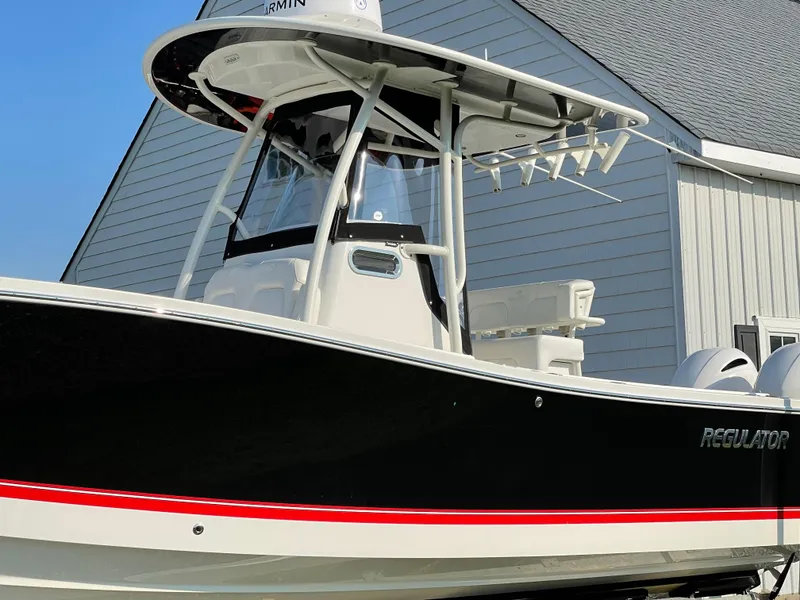 Slide: The Image of 2019 Regulator 23 FS boat with T-top and dual engines, docked near a building. - 9