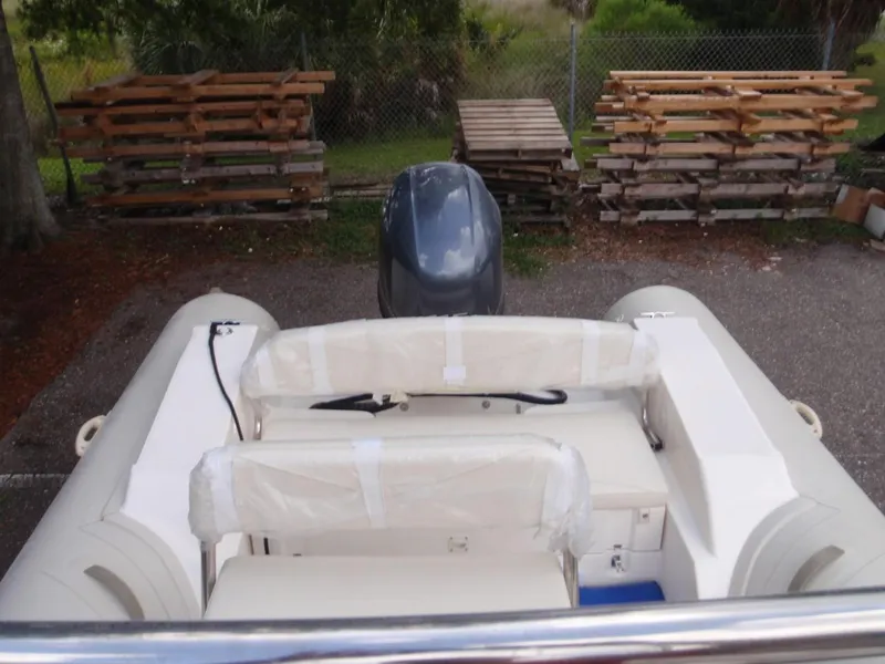 Slide: The Image of 2016 Capelli Tempest 570 inflatable boat with outboard motor, parked near wooden pallets. - 11
