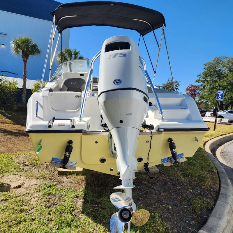 Slide: The Image of 2025 Key West 203 DFS boat with outboard motor, parked on grass. - 2