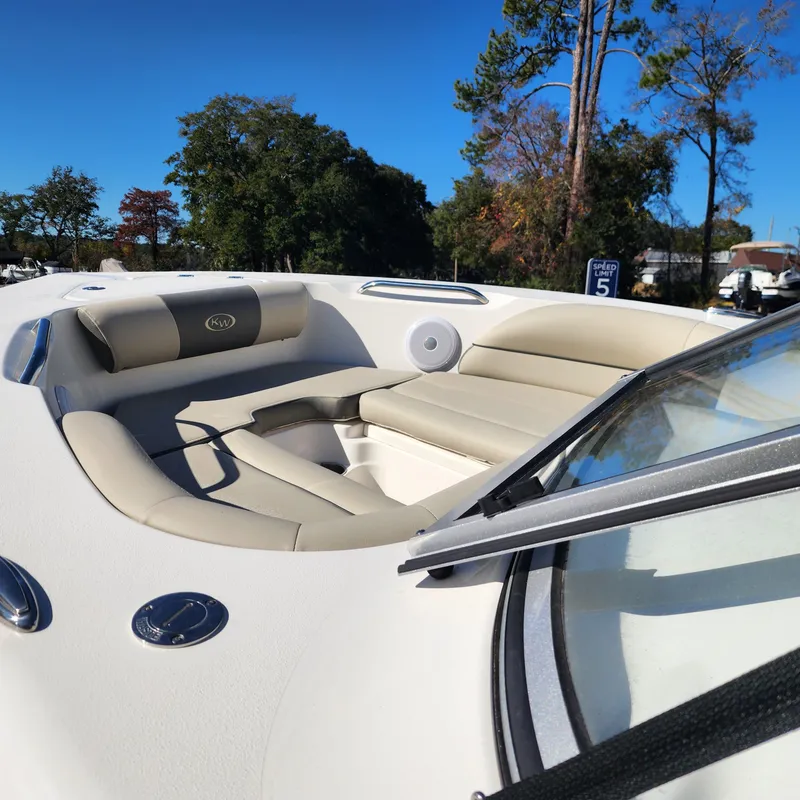 Slide: The Image of 2025 Key West 203 DFS boat interior with beige seating and speaker, surrounded by trees. - 7