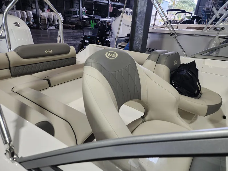 Slide: The Image of 2025 Key West 203 DFS boat interior with beige and gray seating in a marina setting. - 9