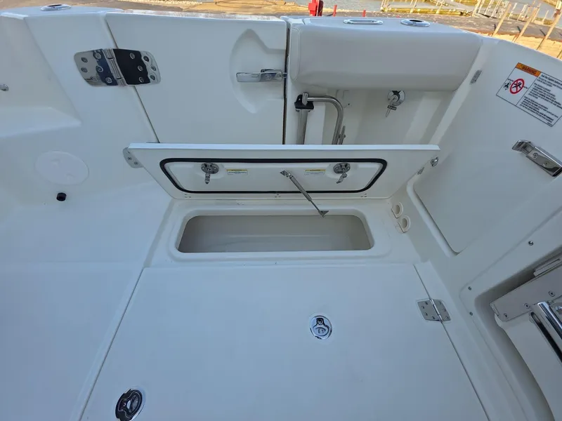 Slide: The Image of 2025 Boston Whaler 325 Conquest deck with open storage compartment and clean white finish. - 11