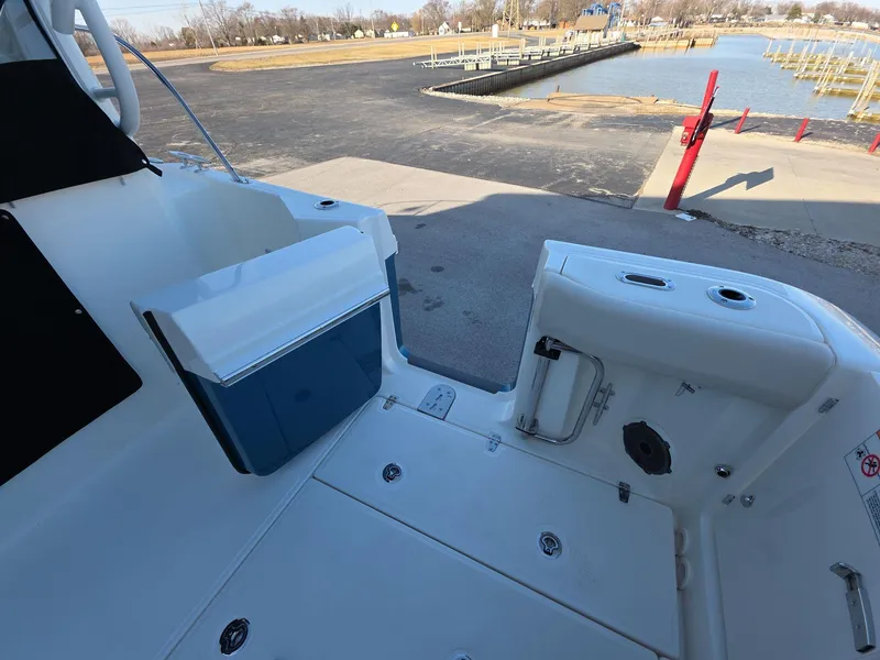 Slide: The Image of 2025 Boston Whaler 325 Conquest boat deck near a dock, showcasing storage and seating. - 15