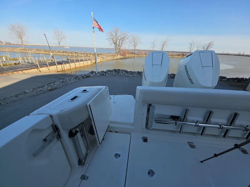 Slide: The Image of Boston Whaler 325 Conquest 2025 boat with dual Mercury engines docked by a lake. - 16