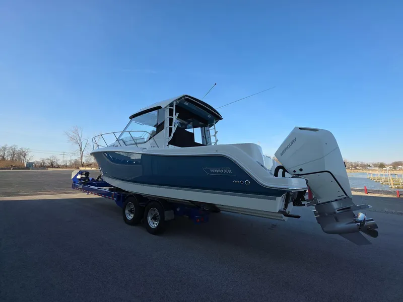Slide: The Image of 2025 Boston Whaler 325 Conquest boat on trailer, parked outdoors under clear blue sky. - 4