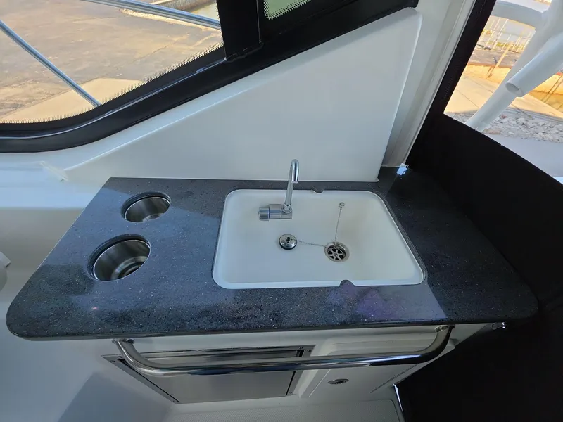 Slide: The Image of Boston Whaler 325 Conquest 2025 boat kitchenette with sink and countertop. - 8