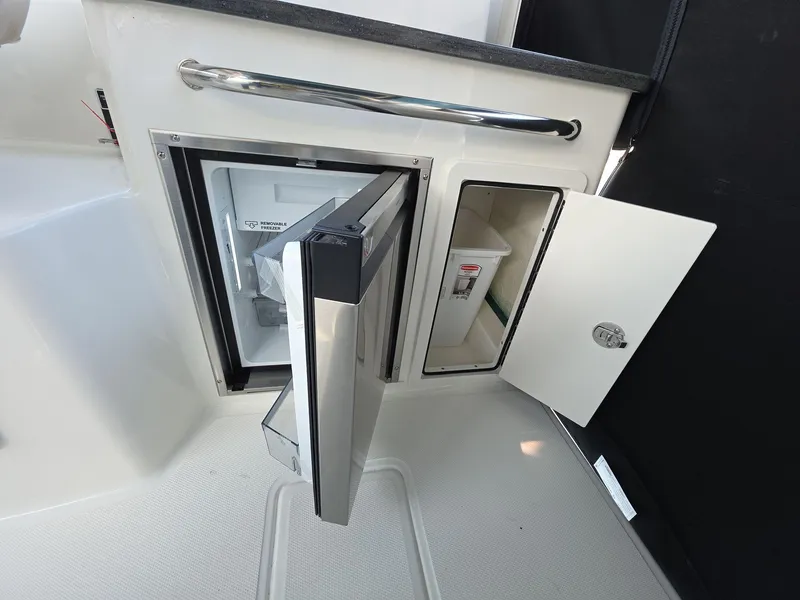 Slide: The Image of 2025 Boston Whaler 325 Conquest interior with open fridge and storage compartment. - 9