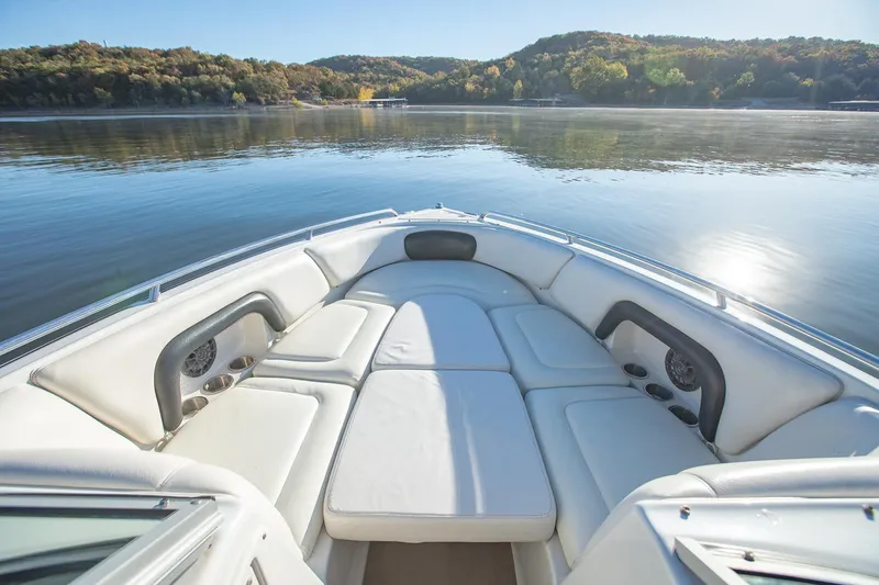 Slide: The Image of 2006 Crownline 270 BR boat interior with white seating on a calm lake. - 11