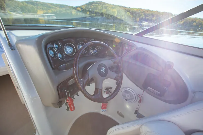 Slide: The Image of 2006 Crownline 270 BR boat dashboard with steering wheel and gauges, scenic lake view. - 33