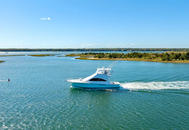 Slide: The Image of 2005 Ocean Yachts 50 Super Sport cruising on a serene waterway under a clear blue sky. - 16
