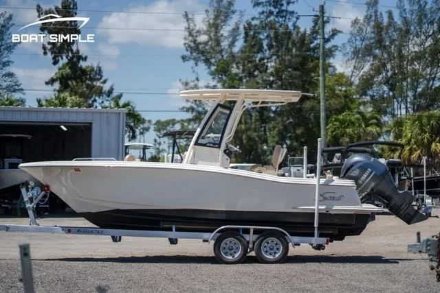 Slide: The Image of 2023 Scout 215 XSF boat on trailer, parked outdoors. - 3
