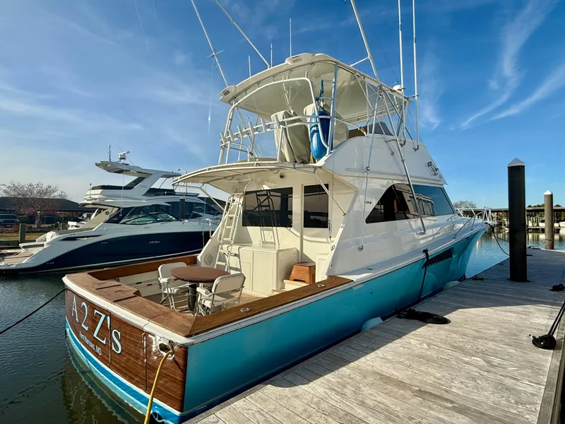 Slide: The Image of 1999 Viking 55 Convertible yacht docked under a clear blue sky. - 2