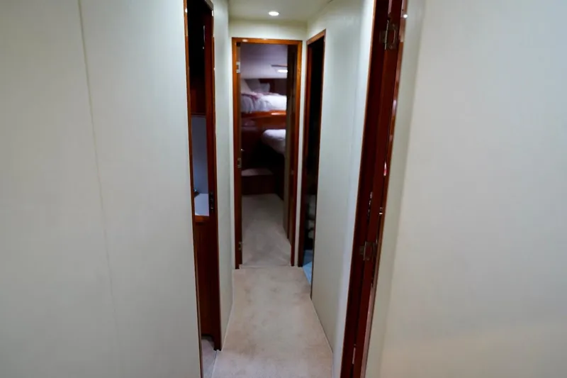 Slide: The Image of Hallway inside 1999 Viking 55 Convertible yacht, featuring wooden doors and carpeted flooring. - 51