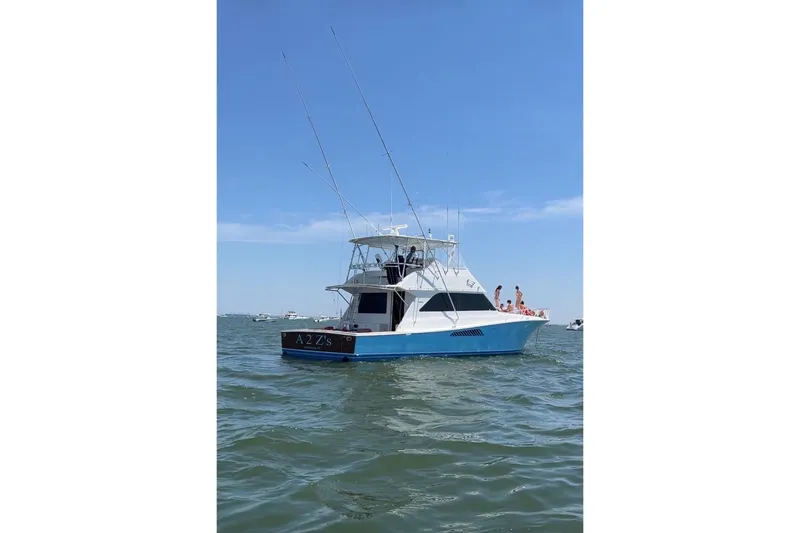Slide: The Image of 1999 Viking 55 Convertible yacht on water, clear sky, people on deck. - 53