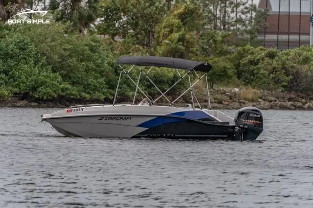 Slide: The Image of 2023 Starcraft SVX 171 OB boat on water with lush greenery background. - 2