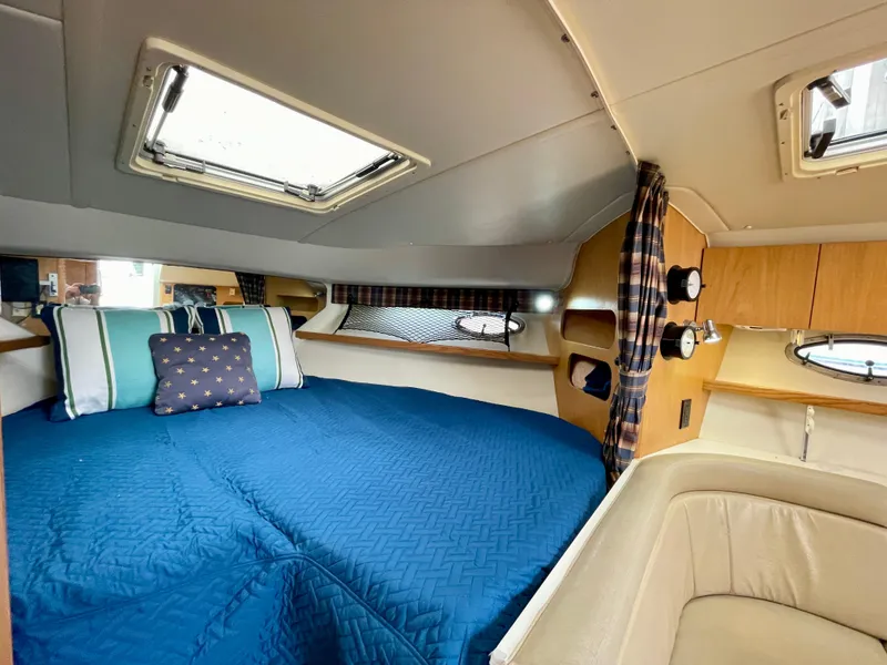 Slide: The Image of 1998 Tiara Yachts 3100 Open cabin with blue bedding and wood accents. - 46