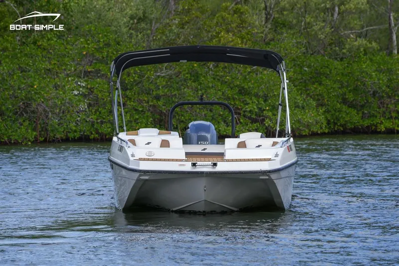 Slide: The Image of 2023 Starcraft SVX 210 boat on water, front view with canopy, lush greenery background. - 1
