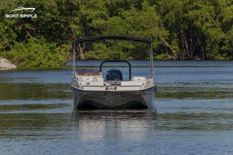 Slide: The Image of 2023 Starcraft SVX 211 OB boat on a serene lake with lush green trees. - 2